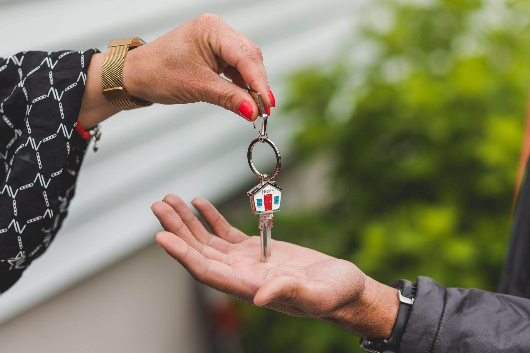 A hand passing a set of house keys to another person