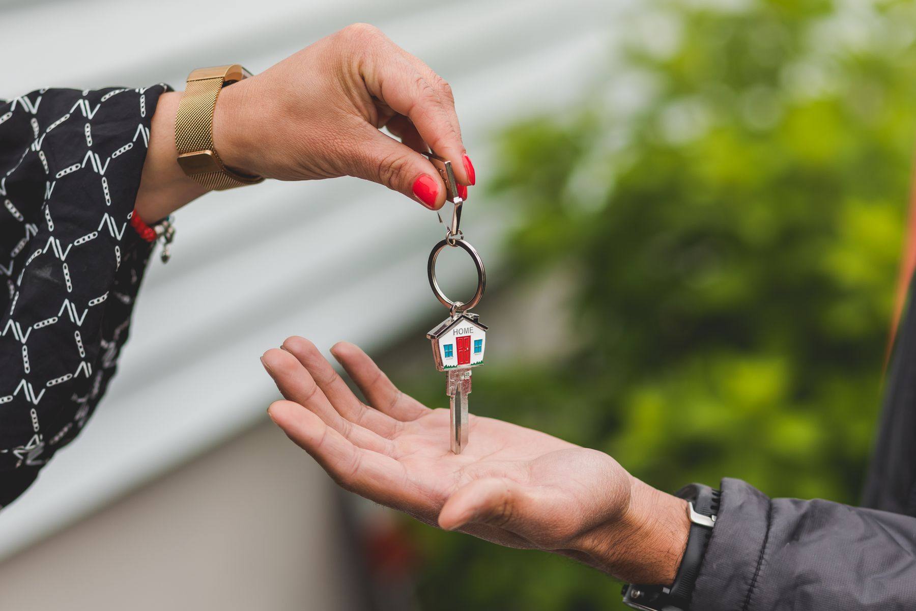 A hand passing a set of house keys to another person