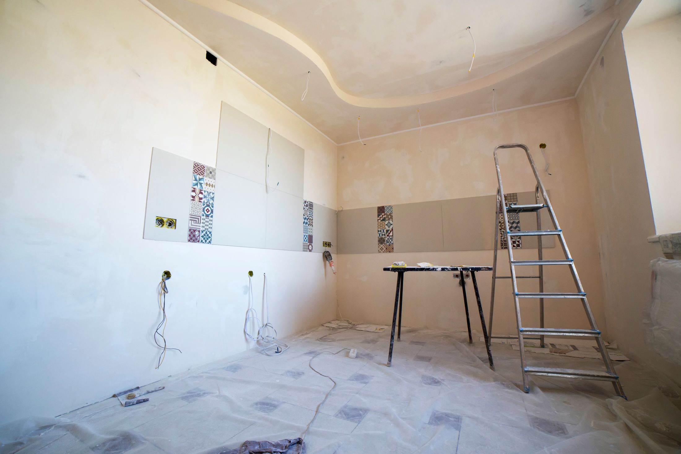 A room mid-renovation, with fresh plaster, a stepladder and dust sheets on the floor