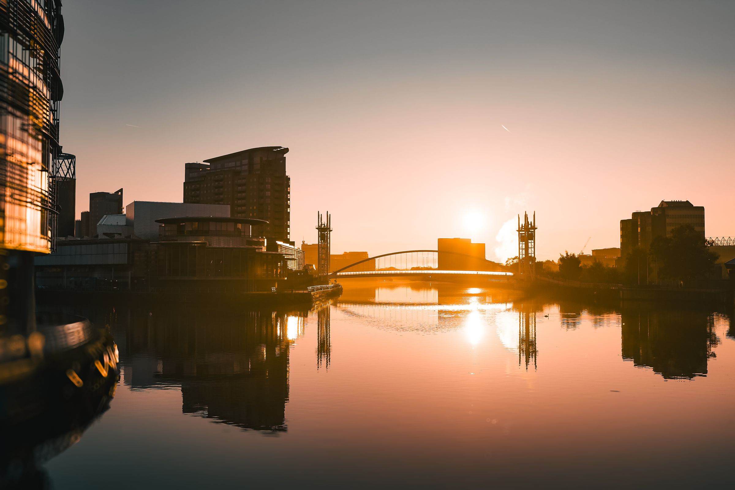 Sunrise over the offices and apartments of Salford Quays, reflected in the water